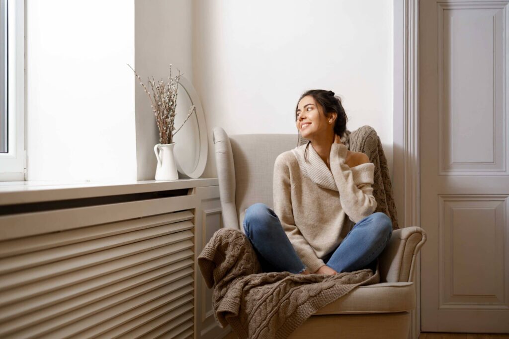 Une femme se détend dans un fauteuil, appréciant une température ambiante idéale pour son confort et sa relaxation.