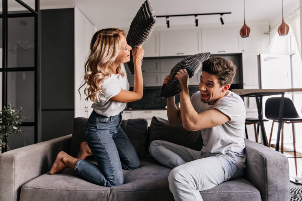 "Dans cette scène chaleureuse, un couple s'amuse avec leurs cousins dans leur salon accueillant. Les rires résonnent et les jeux animent l'atmosphère, créant un moment de joie partagée en famille. Le salon est le témoin silencieux de leur bonheur, empli de souvenirs et d'amour. Une soirée paisible dans leur cocon, où le temps s'arrête, et où ils se créent des moments précieux à deux.