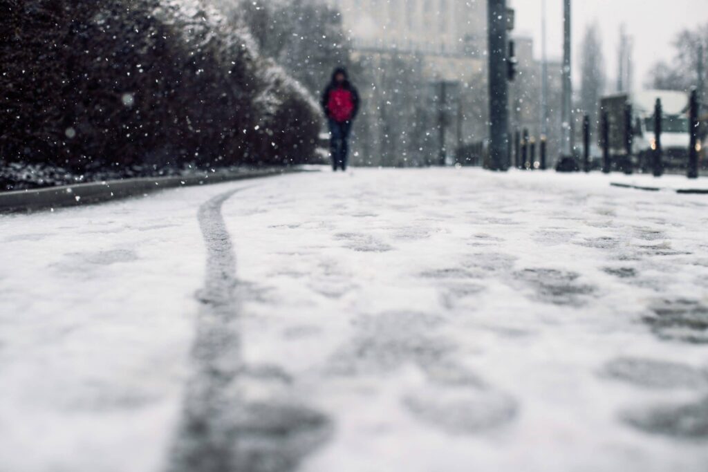 Dans cette scène hivernale, une personne avance d'un pas assuré sur le trottoir enneigé. Les flocons de neige virevoltent doucement autour d'elle, créant une ambiance paisible et féerique. Chaque pas laisse une empreinte fraîche dans la neige, et l'air est empli de la fraîcheur et du silence de l'hiver. La marche solitaire offre un moment de méditation et de contemplation, permettant à chacun de s'immerger dans la magie de la saison froide.